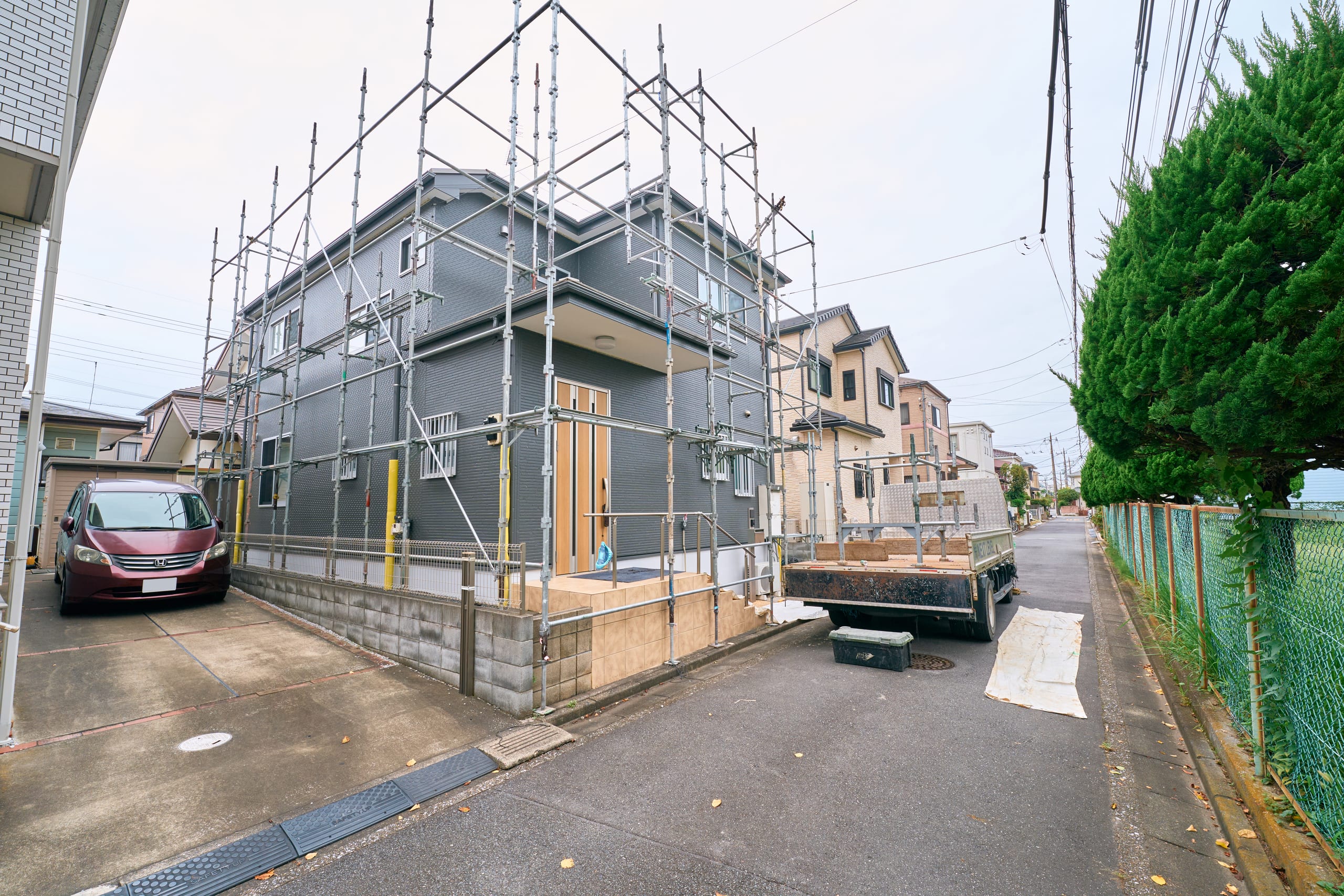 住宅を囲む足場とNEXT LEVELの作業車両