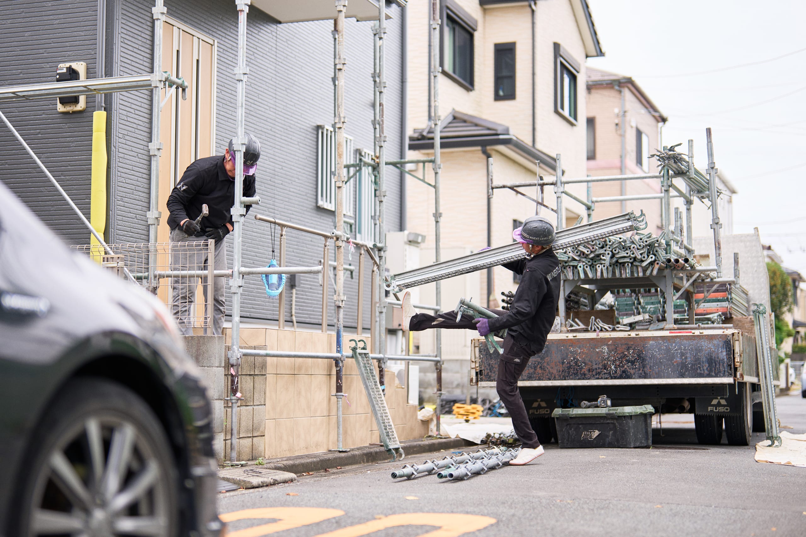 住宅外周で足場を組み立てる作業員